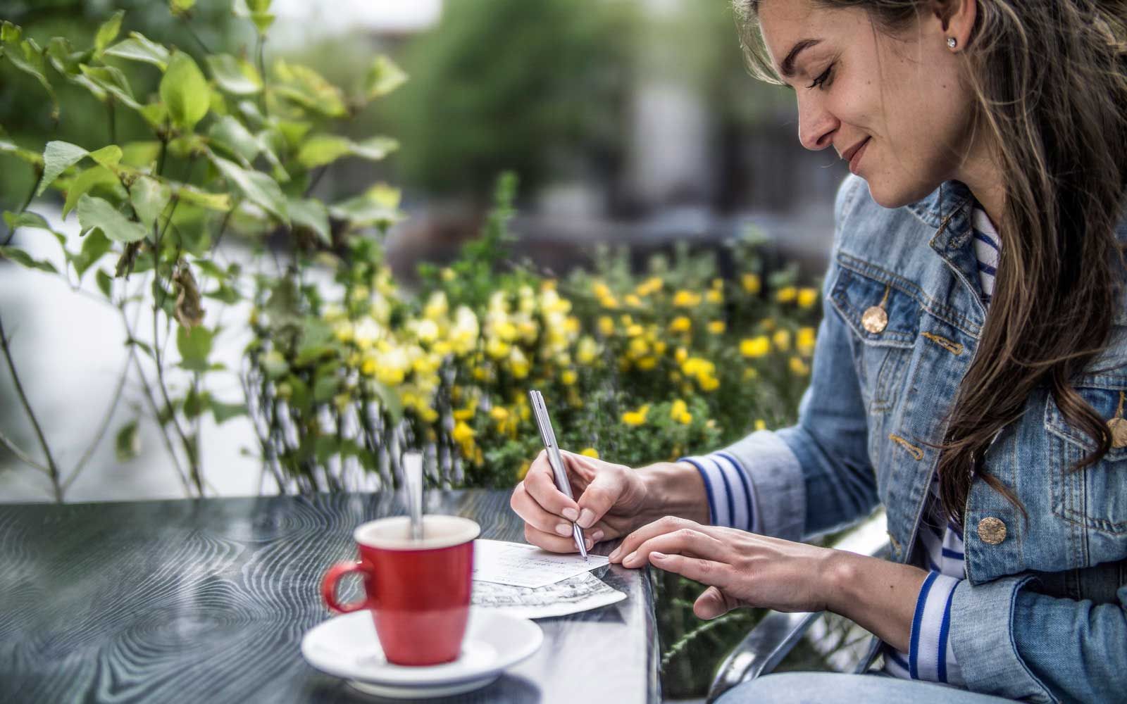 Niederlande, Amsterdam, Frau schreiben Postkarten in einem Straßencafé