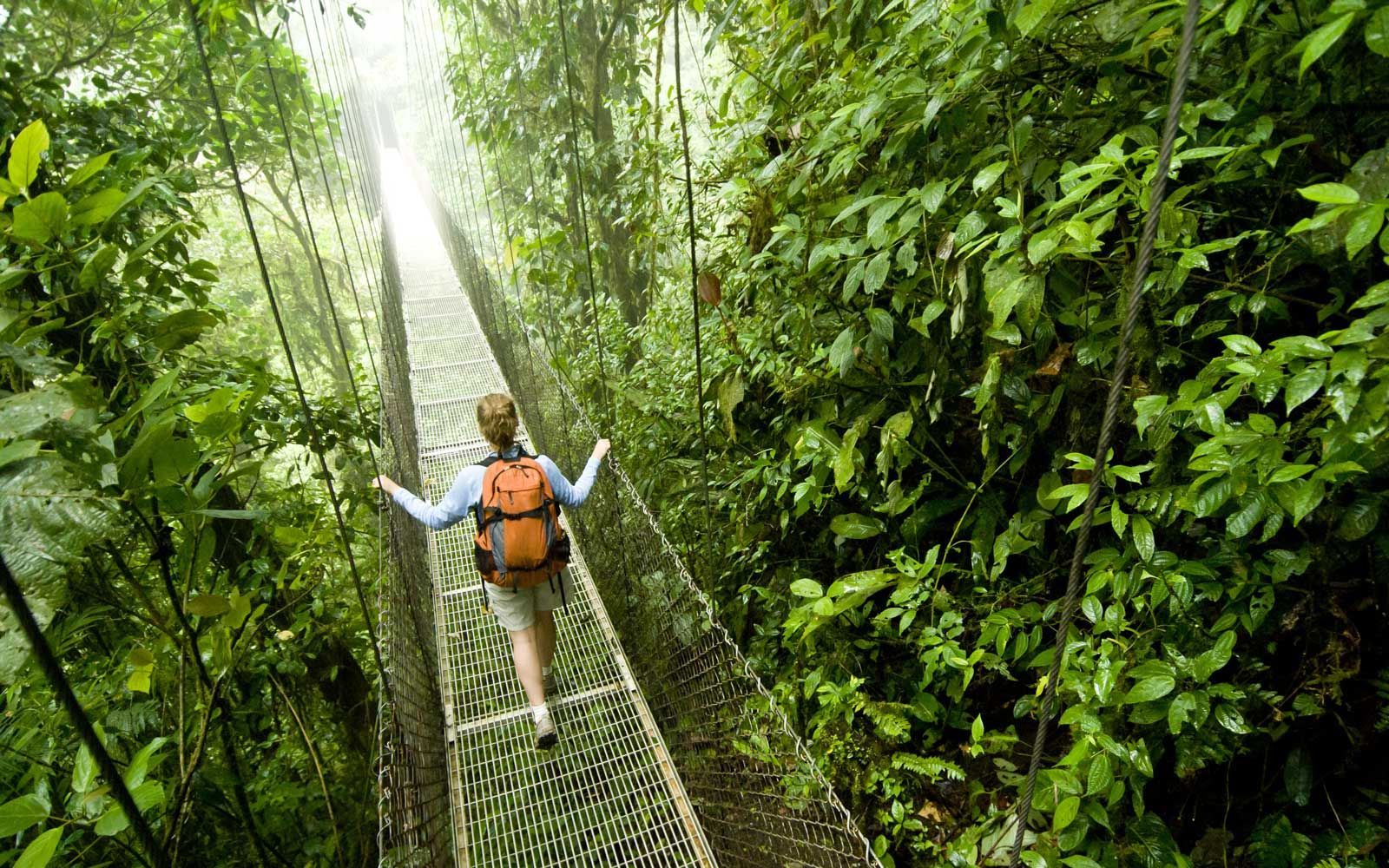 Eine junge Frau wandert entlang einer Hängebrücke in der Nähe des Nationalparks Vulkan Arenal in Costa Rica.