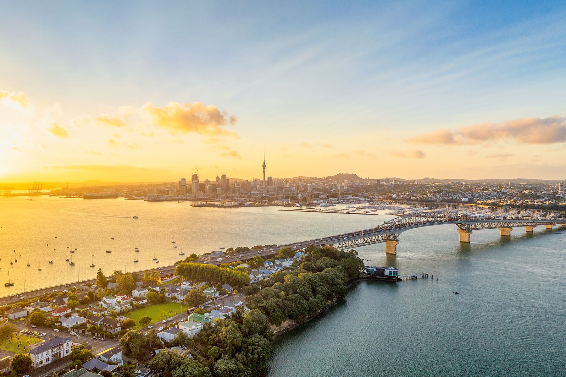 Ein Panoramabild von Auckland von oben mit dem Sky Tower und dem CBD, das über den Waitemata Harbour und die Auckland Harbour Bridge hinweg sichtbar ist.