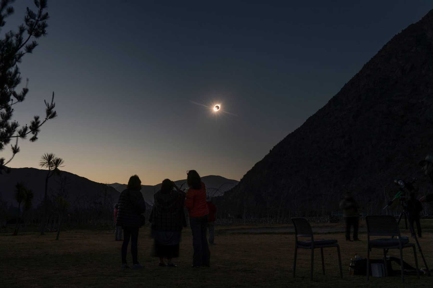 Bidh a ’ghrian a’ nochdadh bho chùl na gealaich mar a bhios daoine a ’coimhead an eclipse grèine iomlan bho El Molle, Chile, air 2 Iuchar, 2019.